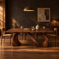 Dining table with a slim top on a looping curved ribbon base in a dark dining room at golden hour