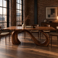 Dining table with a slim top on a looping curved ribbon base in an industrial loft dining room with exposed brick