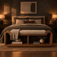 Curved bench with a tufted seat cushion and two open cubbies below in a dark bedroom at golden hour