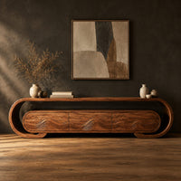 Low tv stand with a looped frame and three wave carved fronts in a dark studio against a charcoal plaster wall
