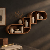 Corner detail of stepped s shaped wall shelf with open cubbies of different sizes beside wood, brass and linen samples