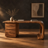 Desk with a drawer pedestal and a curved leg with a round cutout in a dark studio against a charcoal plaster wall