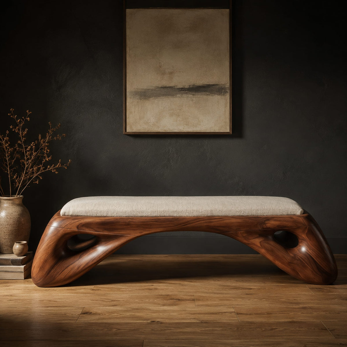 Cushioned bench with a sculpted wood arch base and oval cutouts in a dark studio against a charcoal plaster wall