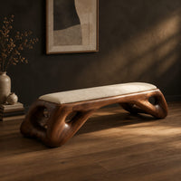 Cushioned bench with a sculpted wood arch base and oval cutouts, three-quarter view showing the grain