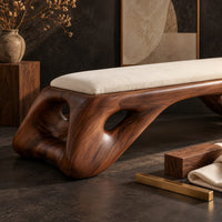 Corner detail of cushioned bench with a sculpted wood arch base and oval cutouts beside wood, brass and linen samples