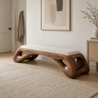 Cushioned bench with a sculpted wood arch base and oval cutouts in a Scandinavian entryway with white walls