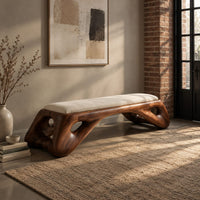 Cushioned bench with a sculpted wood arch base and oval cutouts in an industrial loft entryway with exposed brick