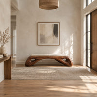 Cushioned bench with a sculpted wood arch base and oval cutouts in a bright open plan entryway