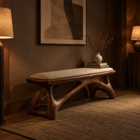 Padded bench with a pale seat on sculpted branching wood legs in an evening entryway with walnut wall paneling