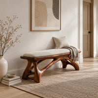 Padded bench with a pale seat on sculpted branching wood legs in a Scandinavian entryway with white walls