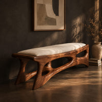 Cushioned bench with a carved open frame and slanted legs, three-quarter view showing the grain