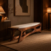 Cushioned bench with a carved open frame and slanted legs in an evening entryway with walnut wall paneling