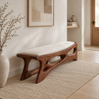 Cushioned bench with a carved open frame and slanted legs in a Scandinavian entryway with white walls