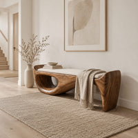 Cushioned bench with a sweeping sculpted body and an oval cutout in a Scandinavian entryway with white walls