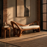 Bench with a cream seat cushion and a sculpted frame full of open cutouts in an industrial loft entryway with exposed brick