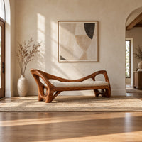 Bench with a cream seat cushion and a sculpted frame full of open cutouts in a bright open plan entryway