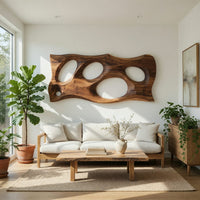 Wooden slab wall art with carved oval openings in a bright sunroom with green plants