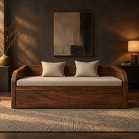 Daybed style sofa with swept wood sides, paneled base and a long seat pad in a dark living room at golden hour