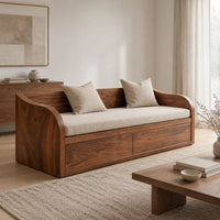 Daybed style sofa with swept wood sides, paneled base and a long seat pad in a Scandinavian living room with white walls