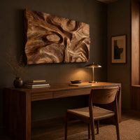 Deep carved wooden wall relief with an oval eye and flowing swirls above a desk in a dark study corner