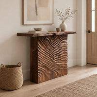 Wooden console table with a live edge top and a deeply carved front in a Scandinavian entryway with white walls