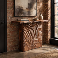 Wooden console table with a live edge top and a deeply carved front in an industrial loft entryway with exposed brick
