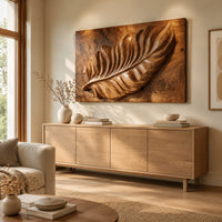 Rectangle wooden wall panel with a deep relief leaf carved across swirling grain above a light oak sideboard in daylight