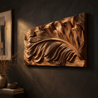 Wide carved wood relief panel of a sweeping feather with flowing layered barbs, three-quarter view showing the carved depth
