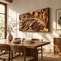 Wide carved wood relief panel of a sweeping feather with flowing layered barbs beside a dining table in natural light