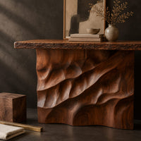 Corner detail of console table with deep diagonal ripple carving on a solid base beside wood, brass and linen samples