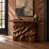 Console table with deep diagonal ripple carving on a solid base in an industrial loft entryway with exposed brick