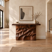 Console table with deep diagonal ripple carving on a solid base in a bright open plan entryway