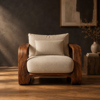 Deep seat lounge chair with thick looped wood arms and a lumbar pillow in a dark studio against a charcoal plaster wall