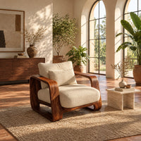 Deep seat lounge chair with thick looped wood arms and a lumbar pillow in a bright living room with arched windows and plants