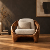 Thick shell wooden chair with wide side openings and cream cushions in a dark studio against a charcoal plaster wall