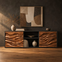Low wooden sideboard with wave carved door panels and an open center bay in a dark studio against a charcoal plaster wall