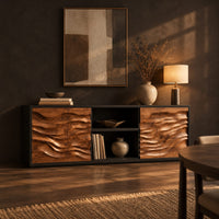 Low wooden sideboard with wave carved door panels and an open center bay in a dark dining room at golden hour