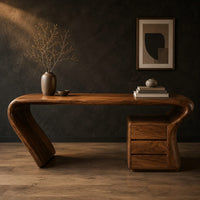 Desk with a top that flows into a slanted leg and drawer pedestal in a dark studio against a charcoal plaster wall