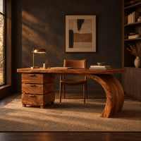 Wood desk with three stacked drawers and one sweeping curved leg in a dark home office at golden hour