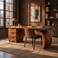 Wood desk with three stacked drawers and one sweeping curved leg in an industrial loft home office with exposed brick