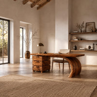 Wood desk with three stacked drawers and one sweeping curved leg in a bright open plan home office