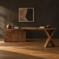 Wooden desk with a wave carved cabinet block and an x shaped leg in a dark studio against a charcoal plaster wall