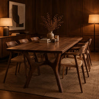 Rectangular dining table with splayed branching legs and an arched cross brace in an evening dining room with walnut wall paneling