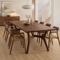 Rectangular dining table with splayed branching legs and an arched cross brace in a Scandinavian dining room with white walls
