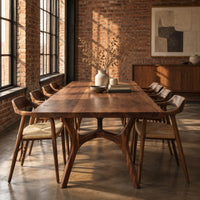 Rectangular dining table with splayed branching legs and an arched cross brace in an industrial loft dining room with exposed brick