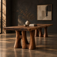 Dining table with a thick slab top on trunk shaped legs with arched openings, three-quarter view showing the grain
