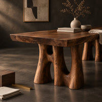 Corner detail of dining table with a thick slab top on trunk shaped legs with arched openings beside wood, brass and linen samples
