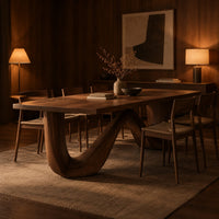 Dining table on a continuous double wave base with a smooth plank top in an evening dining room with walnut wall paneling