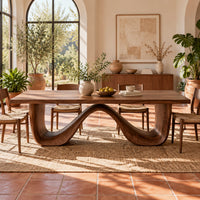 Dining table on a continuous double wave base with a smooth plank top in a bright dining room with arched windows and plants