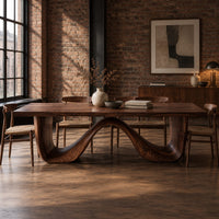 Dining table on a continuous double wave base with a smooth plank top in an industrial loft dining room with exposed brick